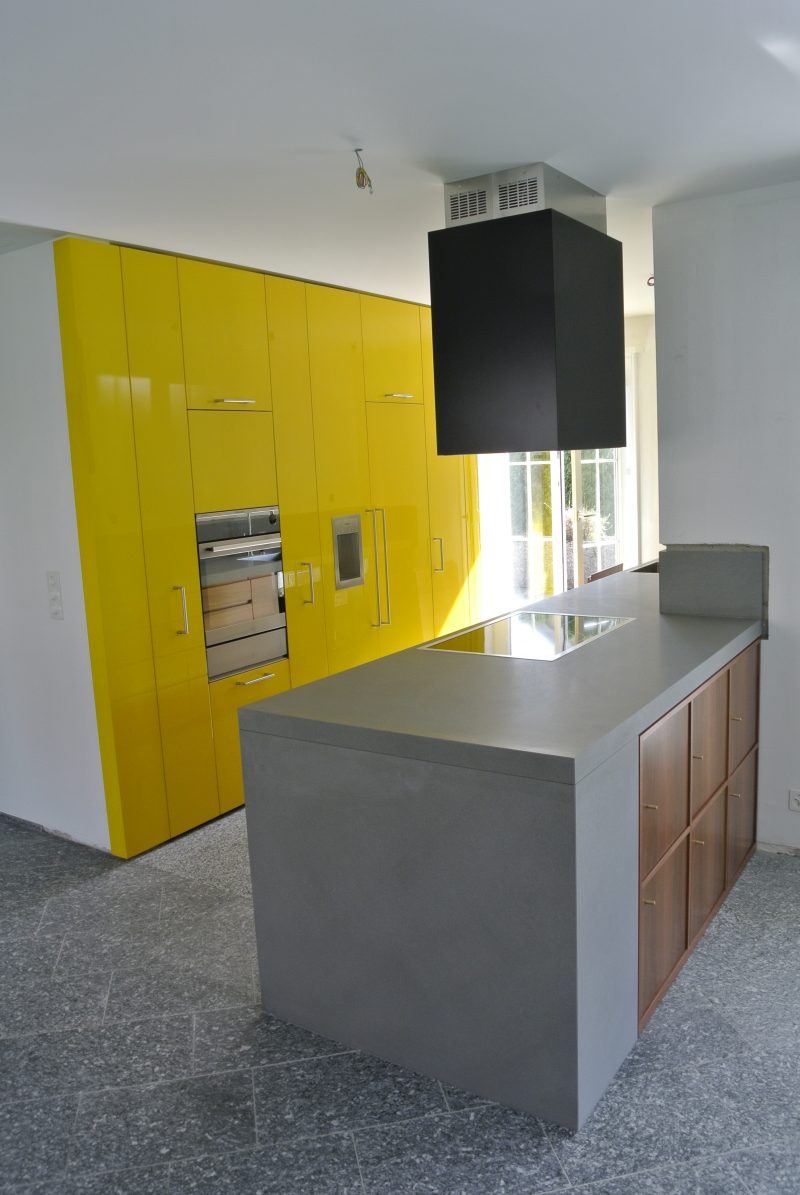 foto di una cucina moderna con parete attrezzata gialla e penisola in pietra e noce nazionale