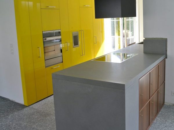 foto di una cucina moderna con parete attrezzata gialla e penisola in pietra e noce nazionale