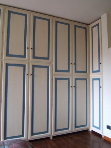 Armadio a muro in legno con ante ad effetto anticato bianco e azzurro.